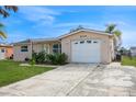 Front view of a single story house with a white garage door and landscaped lawn at 3034 Domino Dr, Holiday, FL 34691