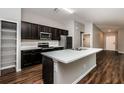 Modern kitchen with dark cabinetry, stainless steel appliances, and breakfast bar at 3843 Laslo Ave, North Port, FL 34287