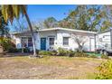 White ranch home with teal door, landscaping, and RV parked at 416 Country Club Dr, Oldsmar, FL 34677