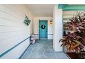 Front entrance with teal door and decorative plants at 7065 Sparkling Creek Ct, Spring Hill, FL 34606