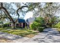 Brick home with paver driveway, lush landscaping, and mature trees at 807 Grove Park Ave, Tampa, FL 33609