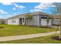 One-story home with gray and white exterior, landscaping, and a paved driveway at 11482 Boundless Ter, Venice, FL 34293