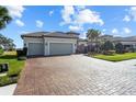 Home exterior featuring a brick driveway, gray garage doors, and a well-maintained front yard at 3404 Forsythia Dr, Odessa, FL 33556