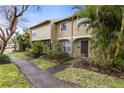 Two story tan townhome with lush landscaping at 7606 Woodbridge Blvd, Tampa, FL 33615