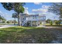Charming stilt home featuring a large deck, lush greenery, and tropical landscaping at 3476 Tidewater Dr, Weeki Wachee, FL 34607