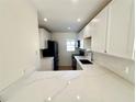 Renovated kitchen featuring white cabinets, quartz countertops, and a breakfast bar at 4511 S Oak Dr # R12, Tampa, FL 33611