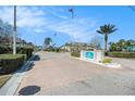 A charming brick paved entrance to Harbor Club lined with lush landscaping and palm trees at 455 Alt 19 S # 268, Palm Harbor, FL 34683