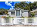 Updated home with gray siding, white picket fence, and landscaped front yard at 1418 E 31St Ave, Tampa, FL 33603