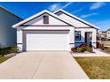 White house with brown accents, a two-car garage, and well-manicured landscaping at 682 Olive Conch St, Ruskin, FL 33570