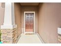Front entry with brown door, stone accents, and a welcome mat at 15571 Stone House Dr, Brooksville, FL 34604