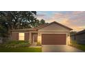 House exterior at dusk showcasing a brown garage door and well-maintained lawn at 15571 Stone House Dr, Brooksville, FL 34604