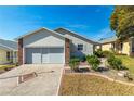 Beige house with double garage and landscaped front yard at 5909 Yorkshire Dr, Zephyrhills, FL 33542
