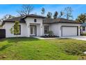 White house with dark gray roof, landscaping, and a two-car garage at 6605 24Th S Ave, Tampa, FL 33619