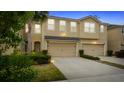 Evening view of tan three-story townhome with two-car garage at 10108 Newel Valley Loop, Riverview, FL 33569