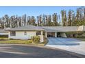 Light beige house with gray roof, carport, and landscaping at 1752 Atrium Dr, Sun City Center, FL 33573