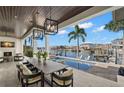 A covered outdoor space including a dining table and outdoor fireplace overlooking the pool and waterway at 2502 S Dundee St, Tampa, FL 33629