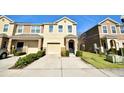 Two-story townhome with tan siding, a two-car garage, and landscaping at 4073 71St N Ter, Pinellas Park, FL 33781