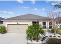 Tan one-story house with a two-car garage and landscaped yard at 12332 Prairie Valley Ln, Riverview, FL 33579