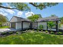 Updated mid-century home with white brick exterior, dark accents, and tropical landscaping at 14040 Cascade Ln, Tampa, FL 33618
