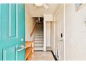 Inviting entryway with teal door, wood shelf, and staircase at 3629 Gulf Blvd, St Pete Beach, FL 33706