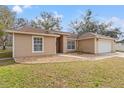 Tan house with a brown roof, white garage door and well-manicured lawn at 5332 Nutcracker Cir, Land O Lakes, FL 34639