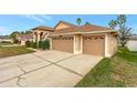 Three-car garage with tan doors and driveway at 10025 Cypress Shadow Ave, Tampa, FL 33647