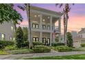 Elegant two-story home with a columned porch, a balcony, an American flag, and mature landscaping at 10444 Green Links Dr, Tampa, FL 33626