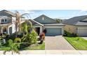 One-story house with gray siding, paver driveway, and palm trees at 15720 Buckford Landing Pl, Sun City Center, FL 33573
