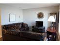 Living room featuring brown leather furniture, wood floors, and a sun wall decor at 711 E Brockton Pl, Sun City Center, FL 33573