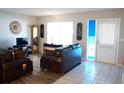 Living room with brown leather sofas, a large window, and tiled floors at 711 E Brockton Pl, Sun City Center, FL 33573