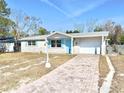 One-story home with light-colored brick exterior, light blue accents, and a brick driveway at 7711 Rottingham Rd, Port Richey, FL 34668