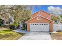 Two-story peach house with white garage door and nicely landscaped yard at 4209 E 98Th Ave, Tampa, FL 33617