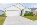 Front view of a white house with a two-car garage and landscaping at 1024 Golden Shiner Ave, Ruskin, FL 33570