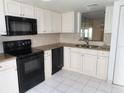 Kitchen with white cabinets, granite counters, and black appliances at 19029 Us Highway 19 N # 23C, Clearwater, FL 33764