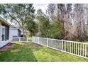 Landscaped backyard with a white fence and mature trees at 30817 Prout Ct, Wesley Chapel, FL 33543