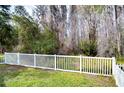 View of backyard through white fence, showcasing lush greenery at 30817 Prout Ct, Wesley Chapel, FL 33543