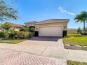 Tan house with tile roof, two-car garage, and landscaping at 4935 Marble Springs Cir, Wimauma, FL 33598