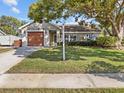 Inviting single-story home with a lush green lawn, mature tree, and a welcoming front entrance at 807 Cavemill Way, Tarpon Springs, FL 34689