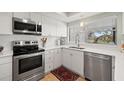 Modern white kitchen with stainless steel appliances and a quartz countertop at 1 Gallinule Pl, Belleair, FL 33756