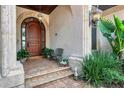 Close-up of front entrance with a wood door, decorative archway, and manicured landscaping at 1097 Eden Isle Ne Dr, St Petersburg, FL 33704