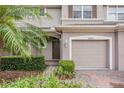 Townhome entrance with a two-car garage and lush landscaping at 26914 Juniper Bay Dr, Wesley Chapel, FL 33544