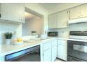 Bright kitchen with white cabinets, appliances, and sink with lemons and pass-through window at 3124 Highlands Blvd, Palm Harbor, FL 34684