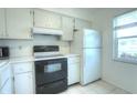 Clean kitchen with ample white cabinetry and black stove next to a white refrigerator at 3124 Highlands Blvd, Palm Harbor, FL 34684