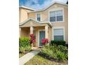 Two-story townhome with light beige exterior, landscaping, and teal door at 5010 Cactus Needle Ln, Wesley Chapel, FL 33544