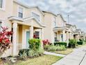 Row of townhomes with light beige exterior, landscaping, and teal doors at 5010 Cactus Needle Ln, Wesley Chapel, FL 33544