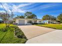 Mid-century modern home with a large driveway and well-manicured lawn at 11388 77Th Ave, Seminole, FL 33772