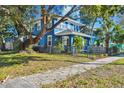 Two-story blue house with a large tree, black fence and stone pathway at 2751 2Nd S Ave, St Petersburg, FL 33712