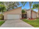 Tan house with white garage door, landscaping, and palm trees at 2826 Kavalier Dr, Palm Harbor, FL 34684