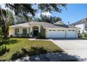 House exterior featuring a three-car garage and manicured lawn at 4996 Felecity Way, Palm Harbor, FL 34685