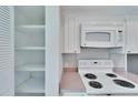 A view of the kitchen shows white cabinets, modern appliances, and open shelving for convenient storage at 8950 Park Blvd # 406, Seminole, FL 33777